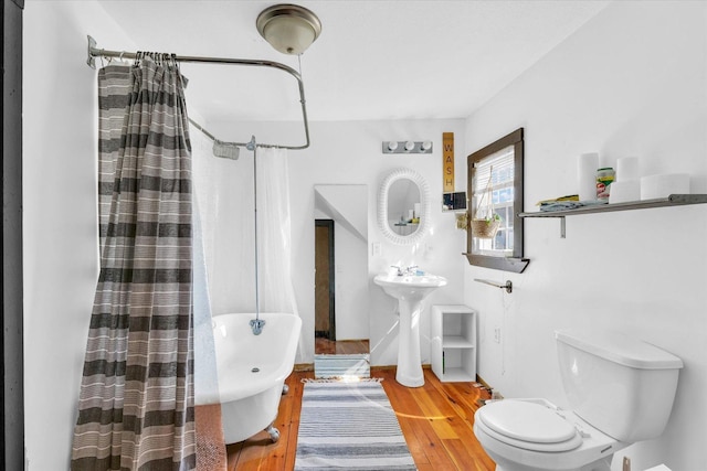bathroom with toilet, a shower with curtain, and wood finished floors