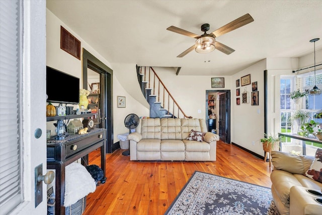 living area with baseboards, ceiling fan, visible vents, stairs, and hardwood / wood-style floors