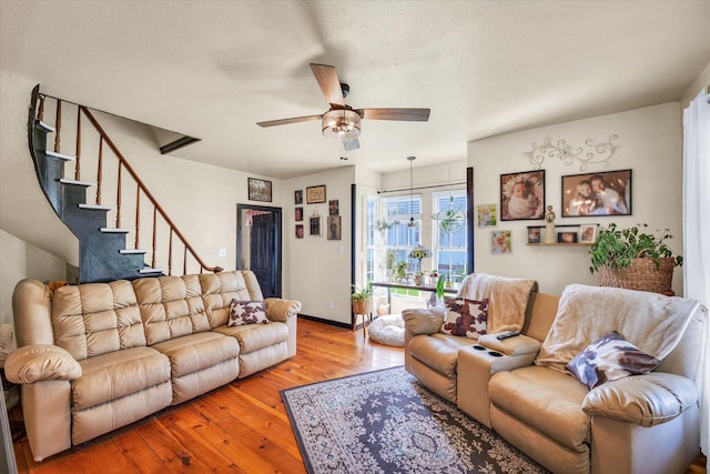 living room with baseboards, hardwood / wood-style floors, ceiling fan, and stairway