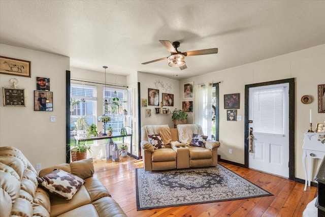 living area featuring light wood-type flooring, ceiling fan, and a textured ceiling
