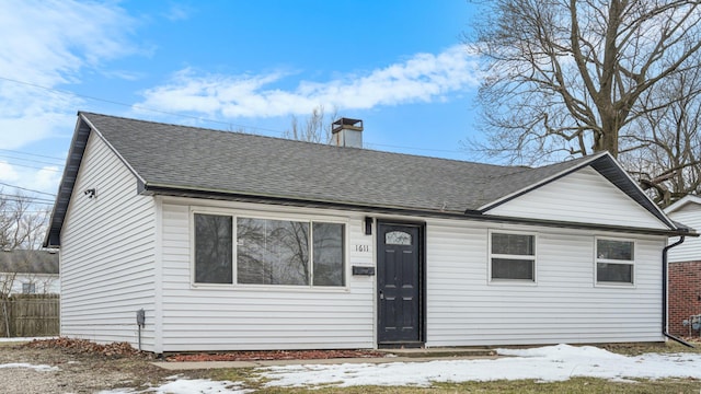 view of front of home with fence, a chimney, and a shingled roof