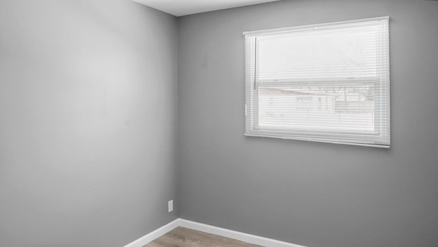 spare room featuring baseboards and light wood-type flooring