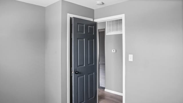 corridor with wood finished floors, baseboards, and visible vents