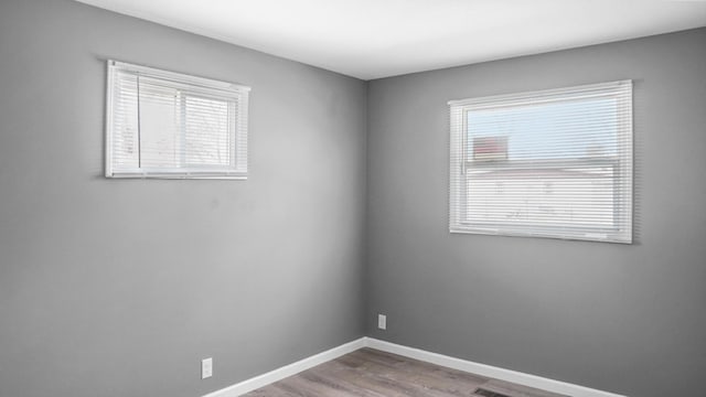 unfurnished room with baseboards and wood finished floors