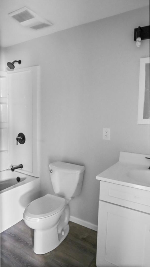 bathroom with vanity, visible vents, toilet, and wood finished floors