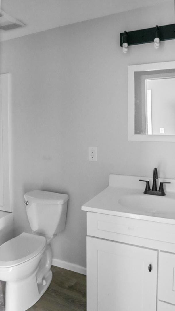 bathroom with visible vents, baseboards, toilet, vanity, and wood finished floors