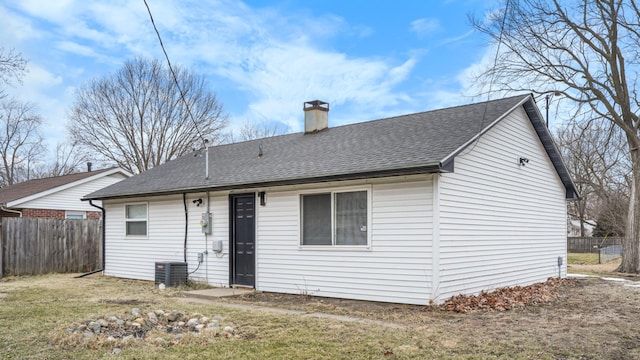 rear view of property featuring central air condition unit, a yard, roof with shingles, fence, and a chimney