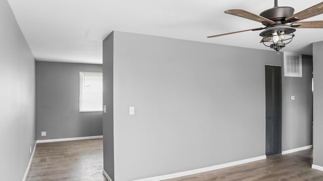 spare room featuring wood finished floors, ceiling fan, baseboards, and visible vents