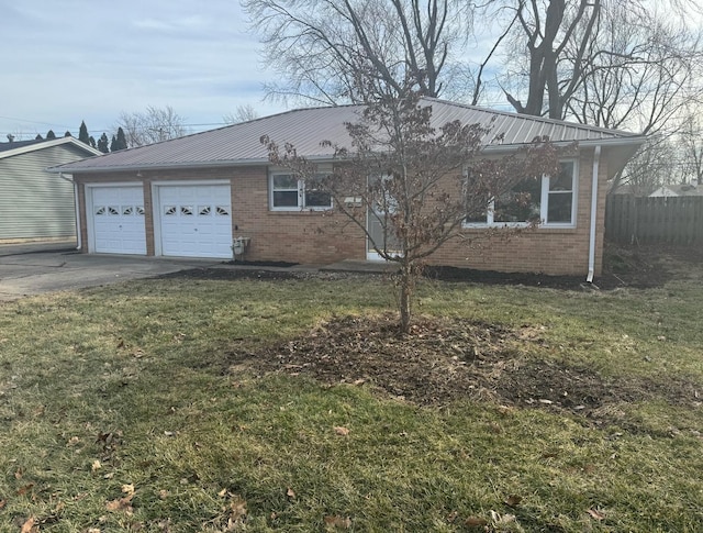 view of front of home featuring metal roof, a front yard, driveway, and brick siding