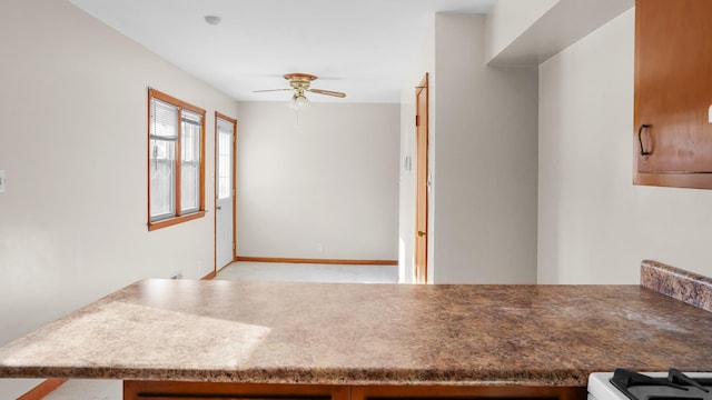 kitchen with ceiling fan, baseboards, and white range with gas stovetop