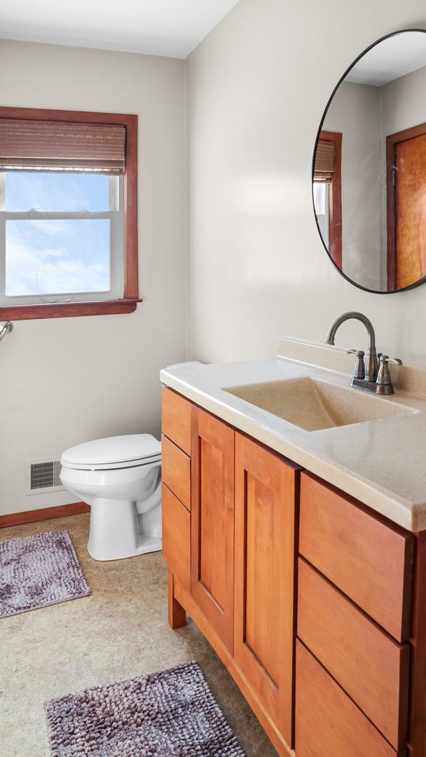 half bathroom with toilet, vanity, and visible vents