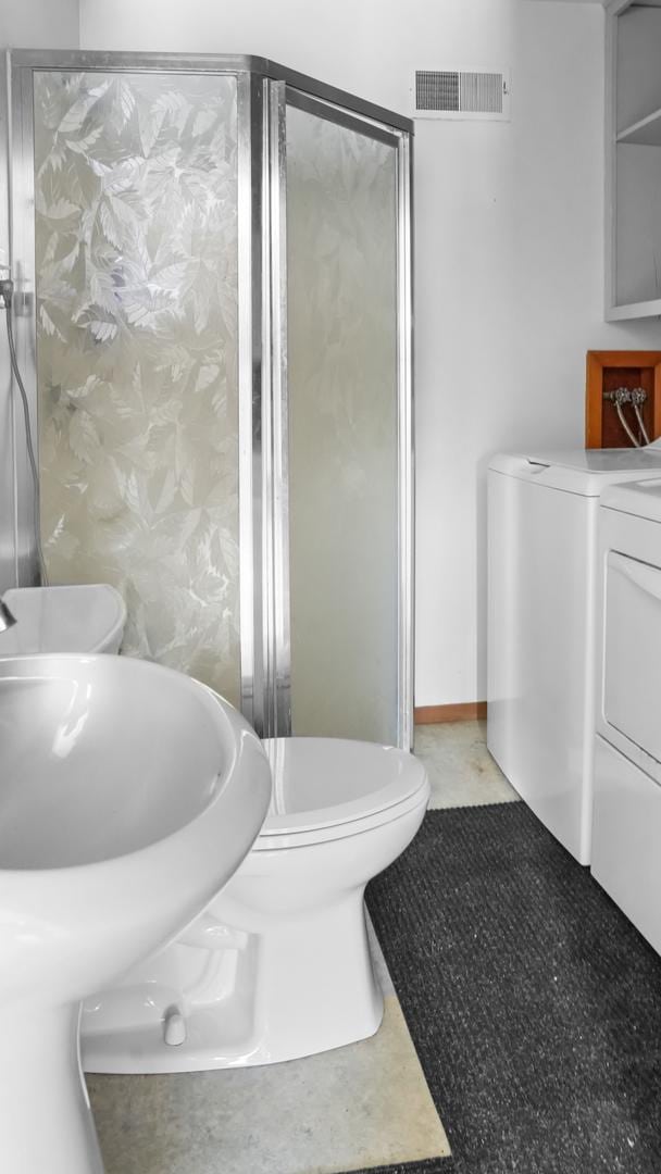 full bath with a shower stall, separate washer and dryer, visible vents, and toilet