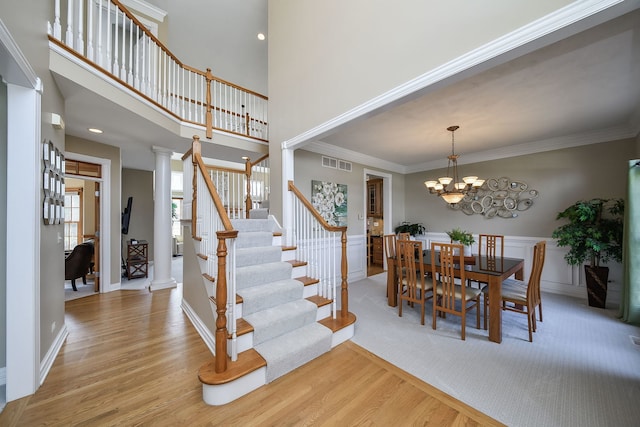 dining room featuring visible vents, crown molding, light wood-type flooring, stairway, and an inviting chandelier