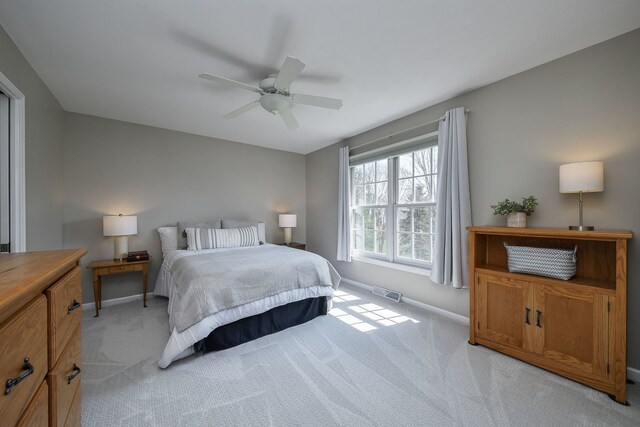 bedroom featuring baseboards, ceiling fan, visible vents, and light carpet