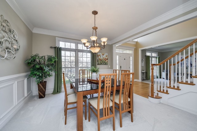 dining room featuring light colored carpet, a chandelier, and ornamental molding