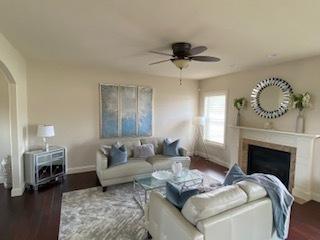 2110 Escalade Rd, Bloomington, IL 61705 - living area featuring ceiling fan, a fireplace, arched walkways, wood finished floors, and baseboards