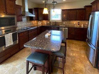 2110 Escalade Rd, Bloomington, IL 61705 - kitchen featuring stainless steel appliances, a wealth of natural light, range hood, and a kitchen bar