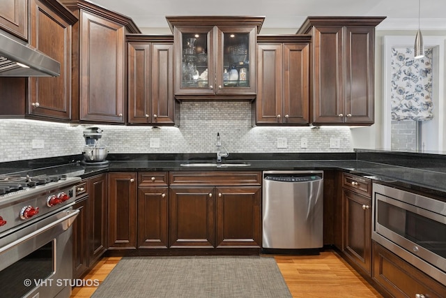 kitchen featuring appliances with stainless steel finishes, a sink, decorative backsplash, and dark stone countertops