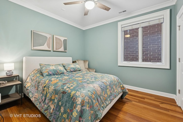 bedroom featuring baseboards, wood finished floors, crown molding, and a ceiling fan