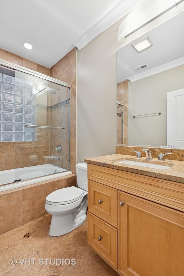 bathroom with toilet, crown molding, tiled shower / bath combo, tile patterned floors, and vanity