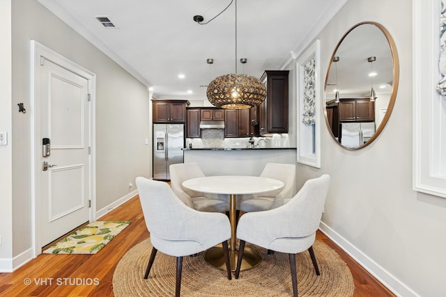 dining room with baseboards, wood finished floors, ornamental molding, and recessed lighting