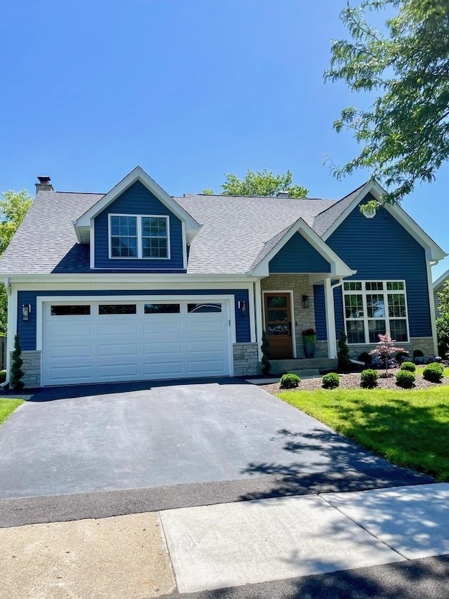 craftsman inspired home with a chimney, a garage, aphalt driveway, a shingled roof, and stone siding