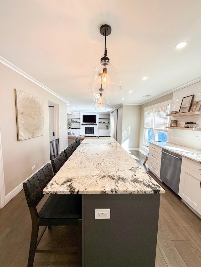 kitchen with crown molding, light stone countertops, a breakfast bar area, and dishwasher
