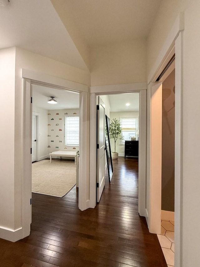 corridor with baseboards, dark wood-style floors, and a healthy amount of sunlight