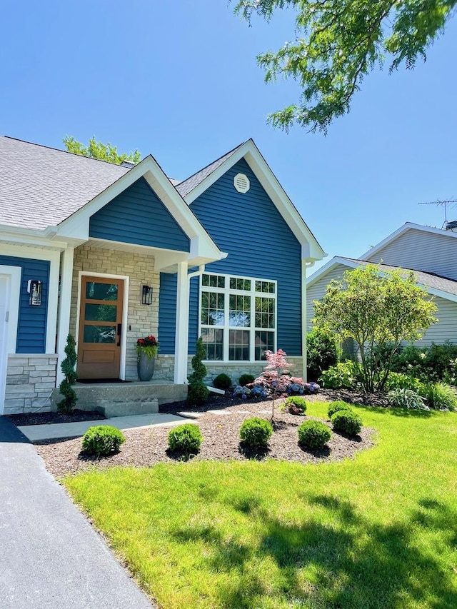 view of front facade featuring a front yard, stone siding, and covered porch