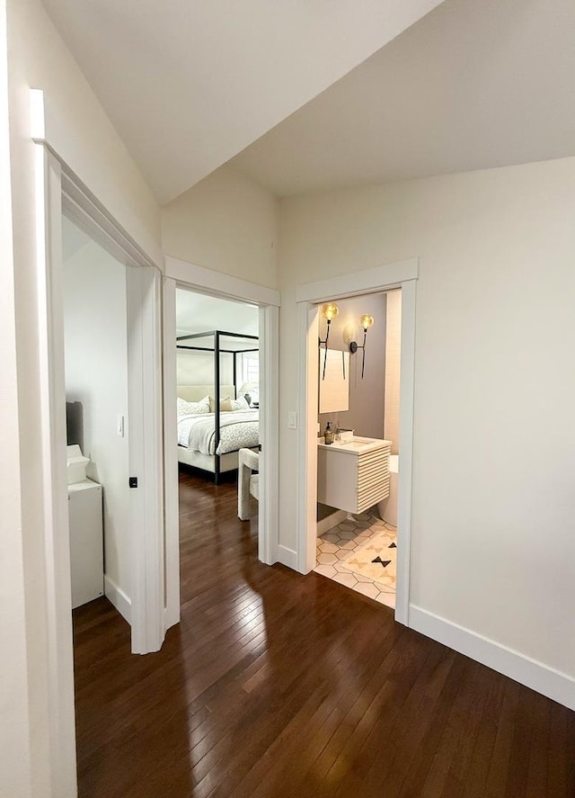 hall with a sink, baseboards, and dark wood finished floors