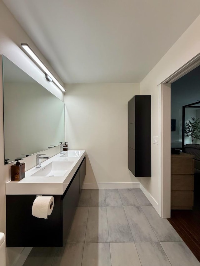 bathroom with double vanity, baseboards, and a sink