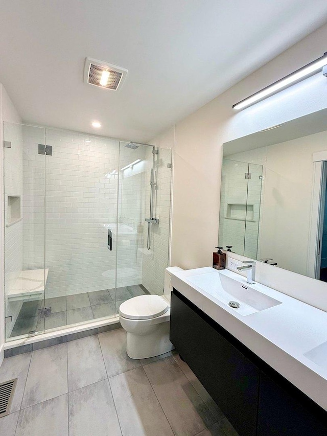 bathroom featuring vanity, a shower stall, toilet, and visible vents