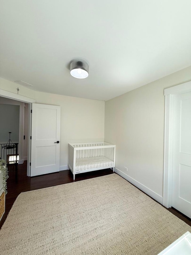 unfurnished bedroom with baseboards and dark wood-type flooring