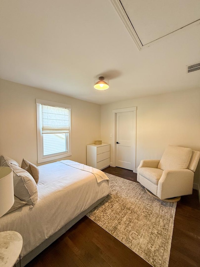 bedroom with attic access, dark wood-type flooring, and visible vents