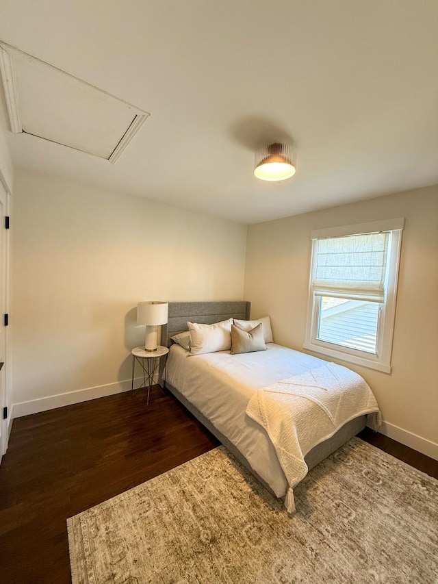 bedroom with baseboards, attic access, and wood finished floors