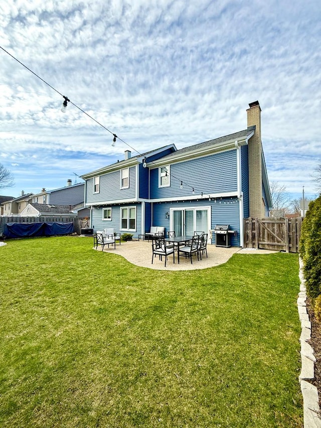 back of house featuring fence, a chimney, a gate, a patio area, and a yard