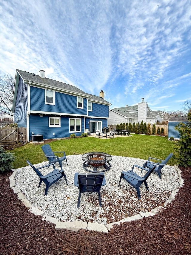 rear view of property with a chimney, a lawn, central AC, a patio, and a fire pit