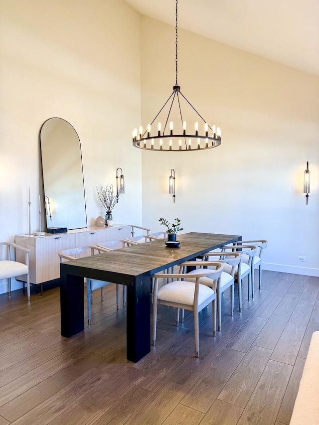 dining area featuring baseboards, a chandelier, wood finished floors, and high vaulted ceiling