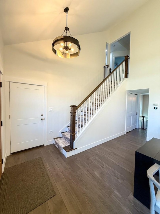 foyer entrance featuring an inviting chandelier, a high ceiling, stairs, and dark wood-type flooring