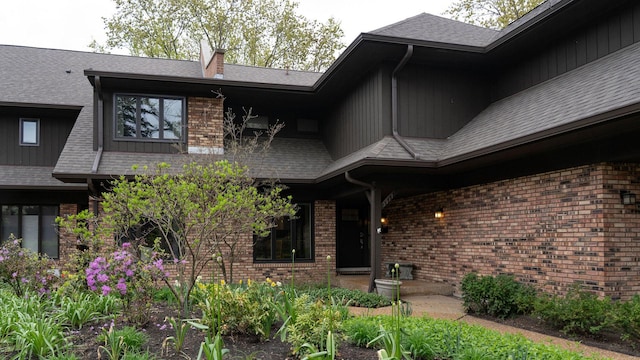 view of exterior entry featuring a chimney and brick siding