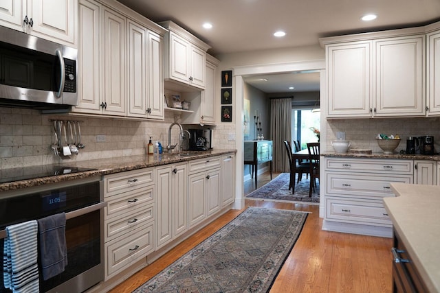 kitchen featuring appliances with stainless steel finishes, tasteful backsplash, light wood-style floors, recessed lighting, and a sink