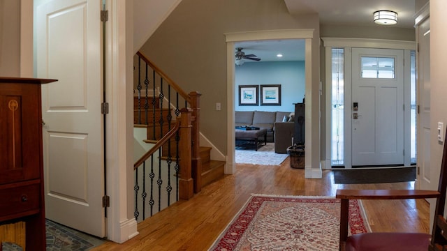 entryway with light wood-type flooring, stairs, and a ceiling fan