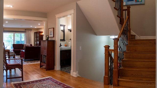 stairs with wood finished floors, recessed lighting, and baseboards