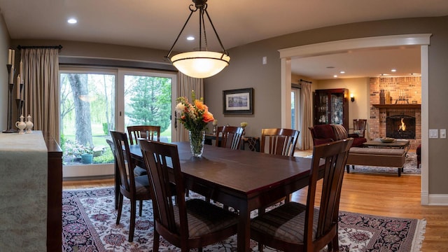 dining space with light wood-style flooring, recessed lighting, and a brick fireplace