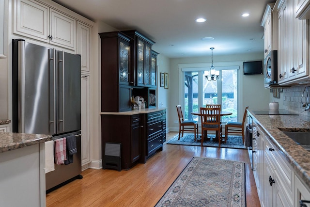 kitchen with stainless steel appliances, light wood-type flooring, glass insert cabinets, recessed lighting, and a chandelier