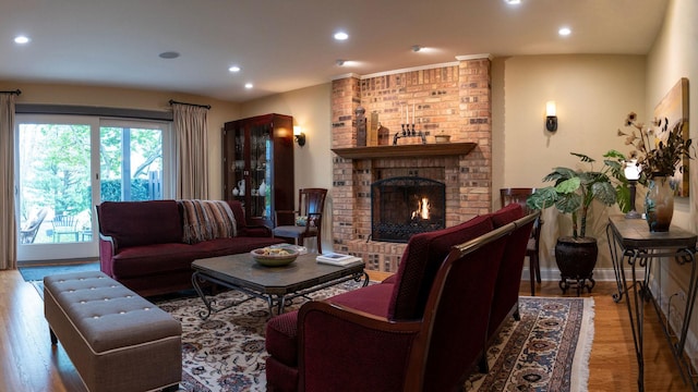 living room featuring wood finished floors, a brick fireplace, and recessed lighting