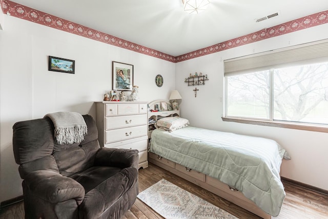 bedroom featuring wood finished floors and visible vents