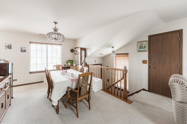 dining space with light carpet, vaulted ceiling, and baseboards