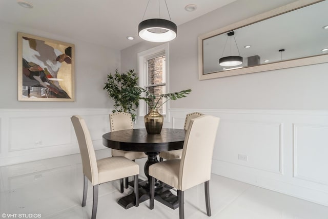 dining room with a decorative wall, recessed lighting, tile patterned flooring, and a wainscoted wall