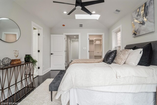 bedroom with ensuite bath, visible vents, lofted ceiling with skylight, and dark wood finished floors